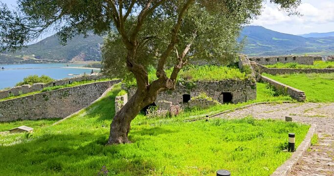 Vonitsa Castle stone courtyard overgrown with grass, landscape view with sea view in the background, Vonitsa, Greece.