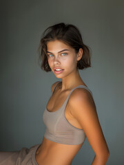 Fototapeta premium Young slim athletic brunette on a gray background. Active lifestyle, weight loss, motivation.