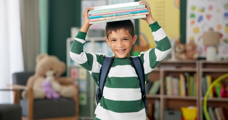 Child, face and book on head with laugh in classroom for learning education for back to school,...