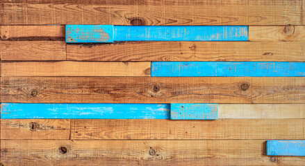 A textured background of a wooden panel made with rustic wooden slats, unpainted wood, and some blue-colored slats.