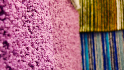Close-up of a purple carpet texture among another carpet samples hanging on the walls