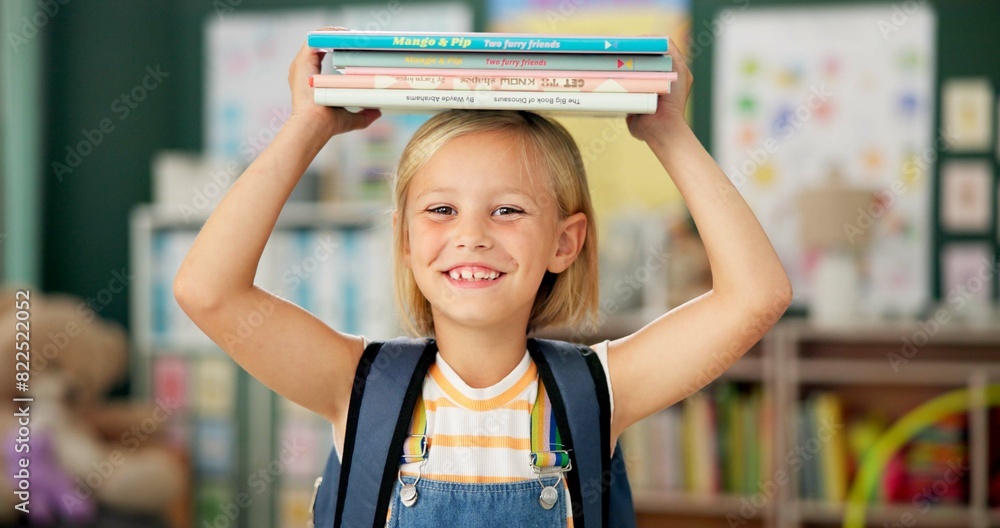 Wall mural Happy, young girl and books on her head in kindergarten school for child development, growth and learning. Smile, female person or student with novel for story time with education, study and reading