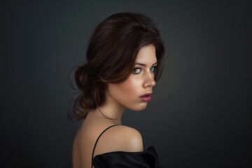 Fototapeta premium Young brunette on a gray background. Feminine beauty.