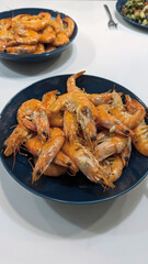 Freshly cooked delicious tiger prawns on a blue plate, isolated on white 