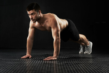 Muscular man, fitness and workout with push ups for exercise, studio or training on a black...