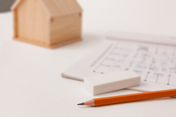 A pencil and a house model placed on a table, representing architectural design and planning.