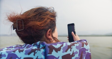 A asian woman is sitting on a longtail boat wearing life jacket looking out nature river lake at...