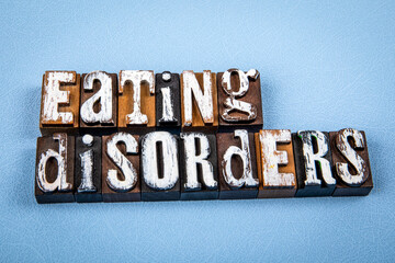 EATING DISORDERS. Wooden alphabet letter blocks on blue textured background