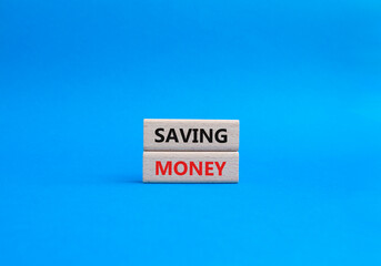 Saving Money symbol. Concept word Saving Money on wooden blocks. Beautiful blue background....