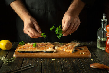 The chef prepares fresh red fish on the kitchen table in the hotel. Before frying, fish steaks are...