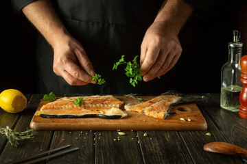 The chef prepares fresh red fish on the kitchen table in the hotel. Before frying, fish steaks are seasoned with aromatic herbs. Asian cuisine.