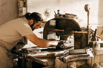 Diabetic Man Operating Hydraulic Press to Mold Cement Tiles in Workshop During Daytime