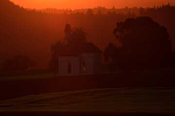 Aufnahme eines ländlichen Sonnenuntergangs mit einer Kapelle.