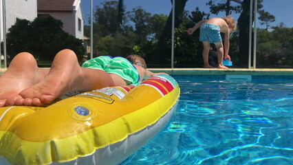 Swimming pool setting, child relaxing on inflatable mattress