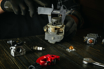 Hands of a craftsman close-up at a work table in a workshop repairing an old engine of a gas mower...