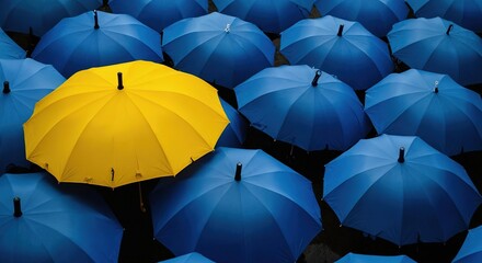 A yellow umbrella that stands out among the blue ones