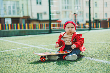 Cute baby sitting on the playground with a skate. Baby on a walk