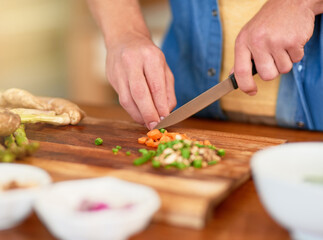 Vegetables, chopping and hand with knife, kitchen counter and cooking for dinner on wood board. House, meal prep and person with carrot for nutrition, healthy food and organic for vegan and closeup