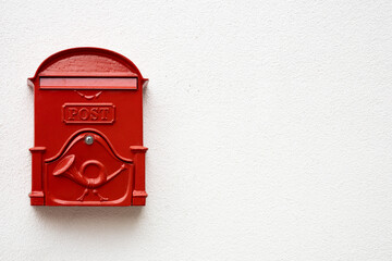 Traditional bright red post box on white plaster texture wall in Hungry. Metal mailbox with text POST in English language. Copy space