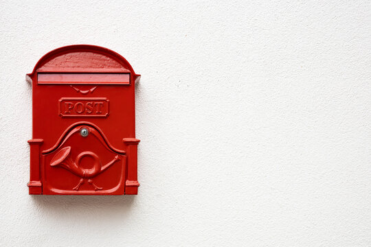 Traditional bright red post box on white plaster texture wall in Hungry. Metal mailbox with text POST in English language. Copy space