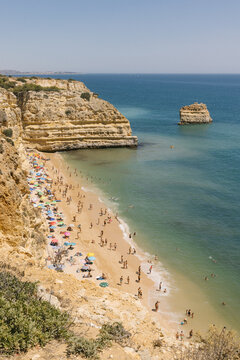 High angle view of rock formations, sandy beaches, and blue ocean on a sunny summer afternoon in Algarve, Portugal. 