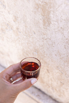 Female hand holding a small shot glass containing gijinha, a sour cherry liqueur in Portugal. 