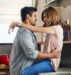 Couple, people and happy with hug in kitchen counter to relax for bonding, love and support on...