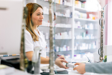 Woman pharmacist  consulting customer at counter for prescription drugs or medicine at the...