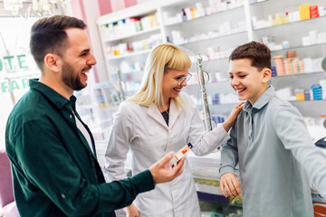 Cheerful pharmacist chemist woman giving vitamins, medicine to father and son.
