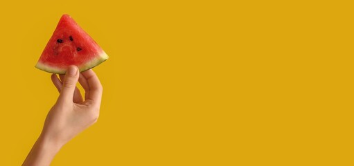 Female hand holding watermelon slice on yellow background with space for text
