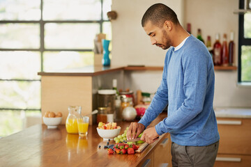 Cooking, man and cutting fruits for breakfast, nutrition or hungry for natural healthy diet in home...