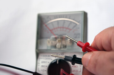 Electrician working with analog multimeter. Focused on probes.
