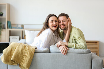 Happy young couple sitting on sofa at home