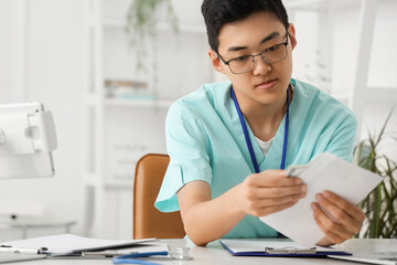 Male Asian doctor with envelope of money in clinic