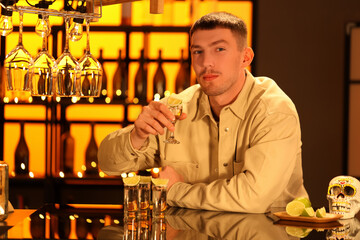 Young man with tequila shot in bar at night