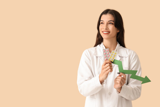 Female doctor with arrow and pills on beige background. Price decline concept