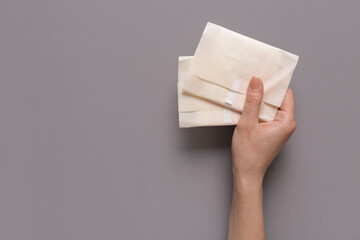 Female hand with menstrual pads on grey background