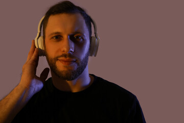 Young man in modern headphones on dark background
