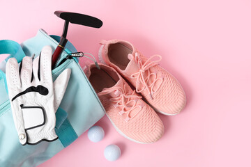 Sports bag with golf equipment and shoes on pink background