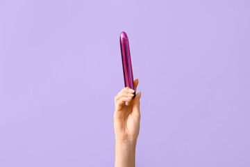 Female hand with vibrator on lilac background, closeup