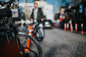 Selective focus on a bicycle wheel with a vibrant city street and pedestrians blurred in the...