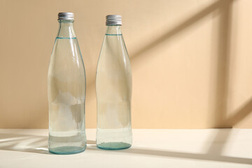Bottles of clean water on table near beige wall