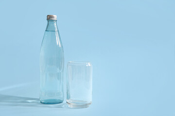 Bottle of clean water and glass on blue background