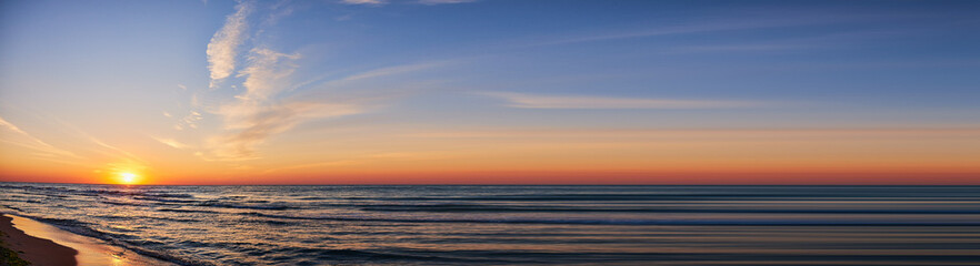 A sunset over a waves sea. Abstract summer banner of cloudy sky.