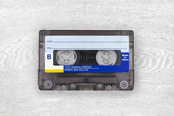 Retro cassette tape on a textured white wooden surface.