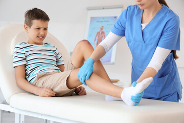 Little boy with injured leg visiting doctor in clinic