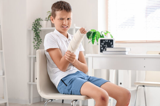 Injured little boy with bandaged arm sitting in clinic - Powered by Adobe