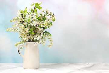 Beautiful spring blooming apple and bird cherry branches in a vase on an elegant background, banner. Abstract flower arrangement, still life with space for text, floral holiday card, 