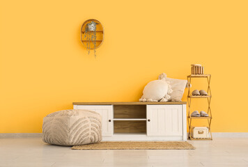 Chest of drawers with pillows, shelving unit with slippers and pouf in living room