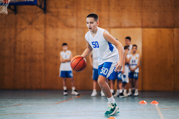 Junior basketball player dribbling a ball at indoor court on training